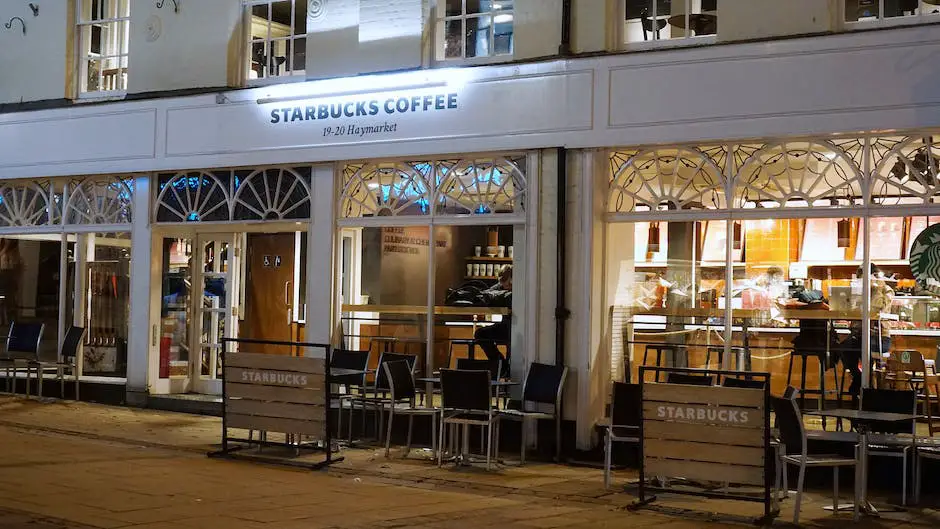 A picture of a Starbucks store in a European city surrounded by locals enjoying their coffee and pastries inside and outside the store.